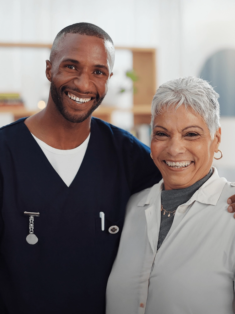 Smiling MobileCare healthcare professional in uniform standing in front of company logo at medical office.