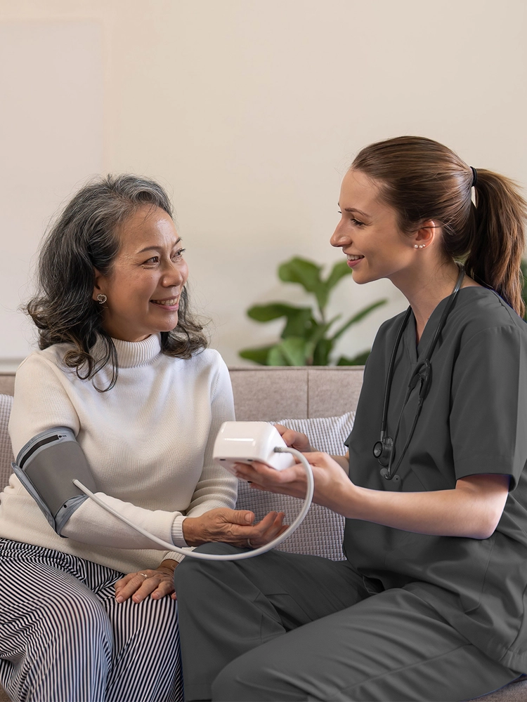 Nurse providing at-home chronic care support, helping a senior patient manage their health.