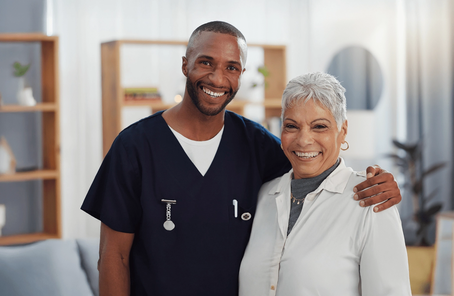 Smiling MobileCare healthcare professional in uniform standing in front of company logo at medical office.