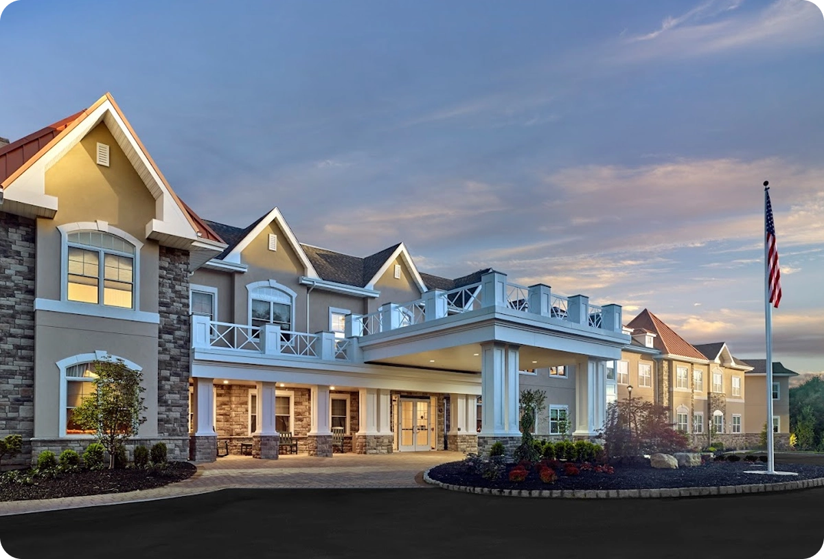 Exterior view of a modern, well-lit assisted living facility at dusk, showcasing Life Medical partner communities